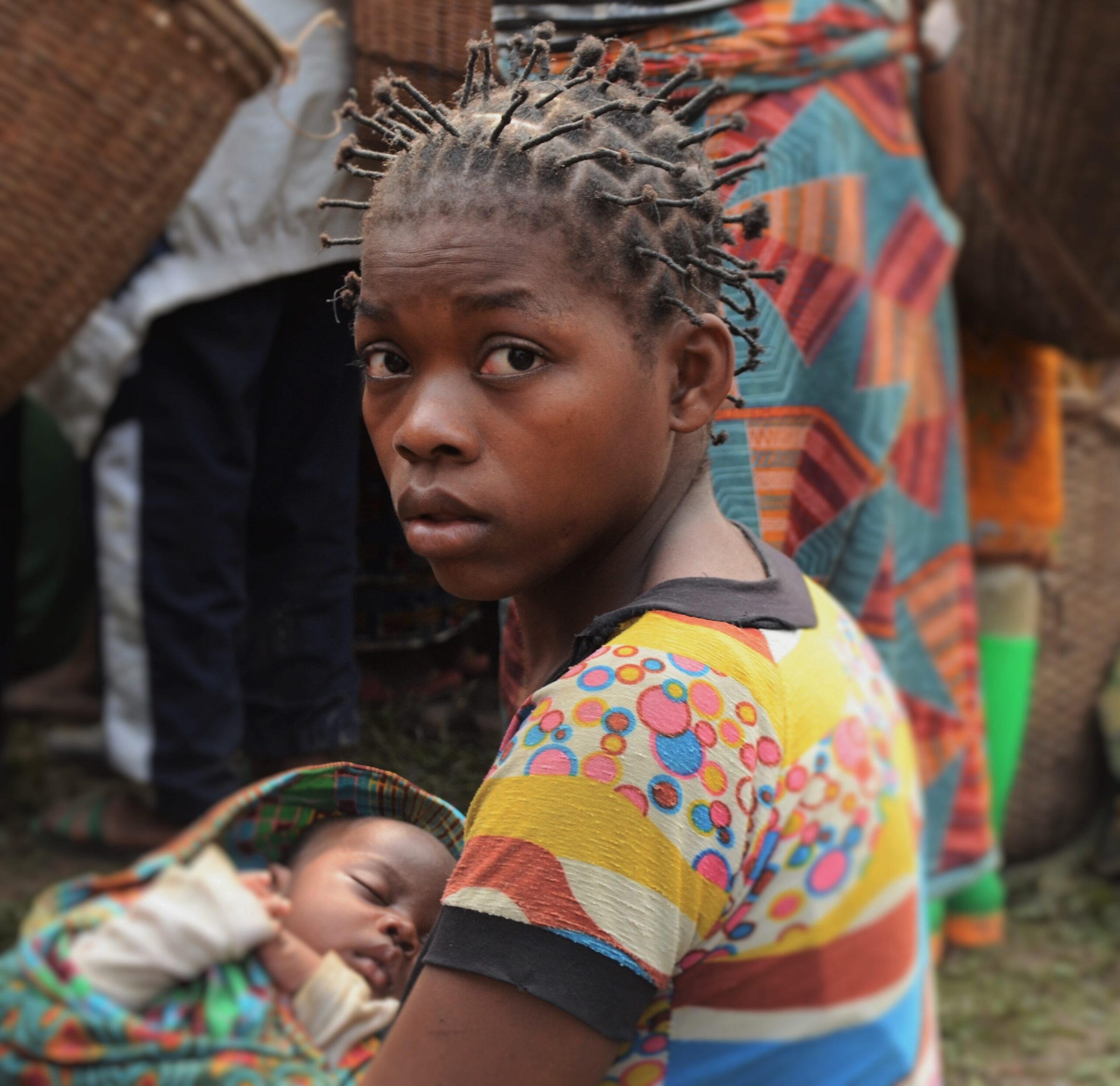 Young woman holding a sleeping baby in a rural community setting
